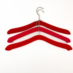 Drei rote Retro-Kleiderbgel mit Strickberzug