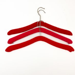 Drei rote Retro-Kleiderbgel mit Strickberzug