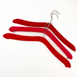 Drei rote Retro-Kleiderbgel mit Strickberzug
